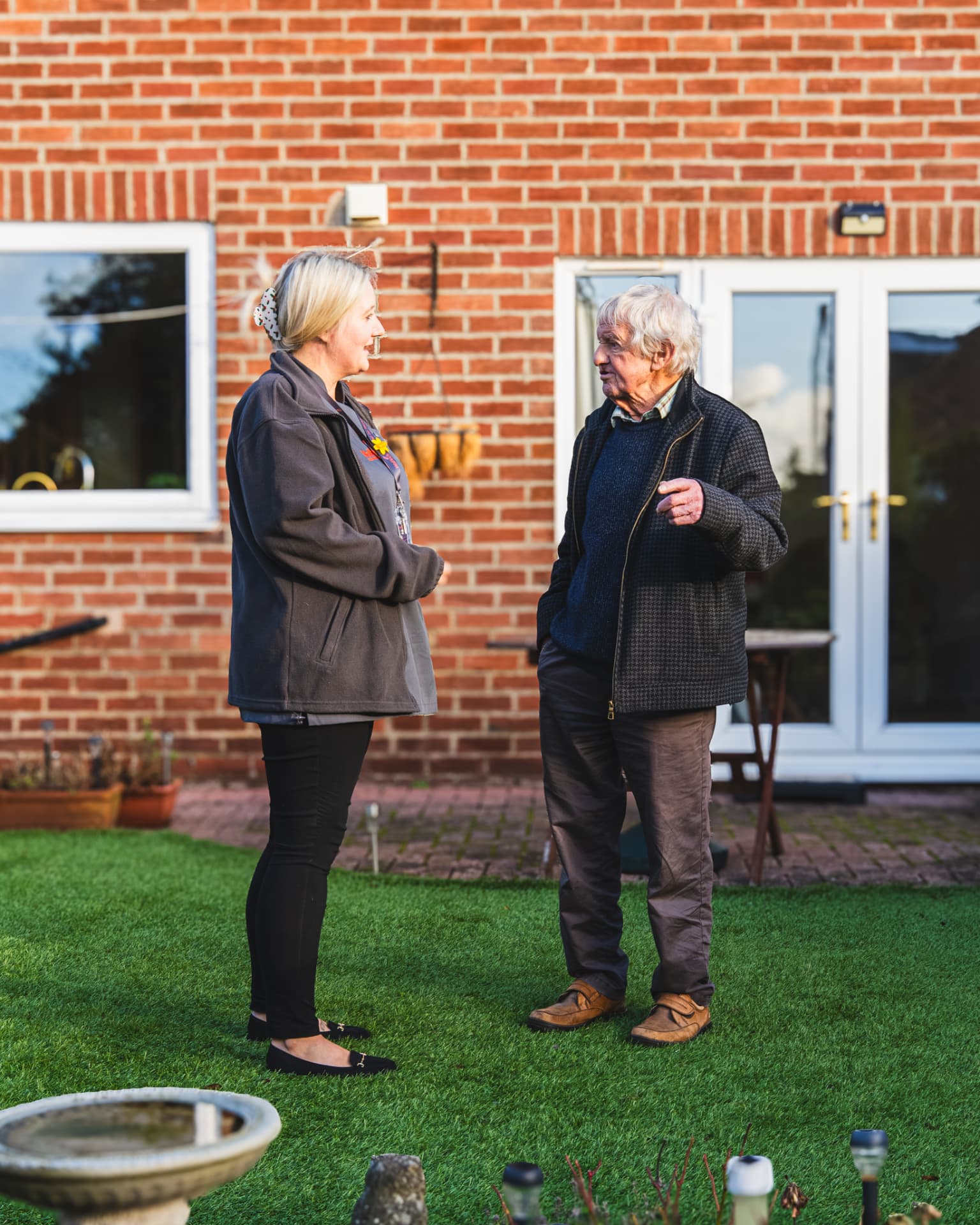 A Walfinch Newcastle carer chatting with an older client in his garden.