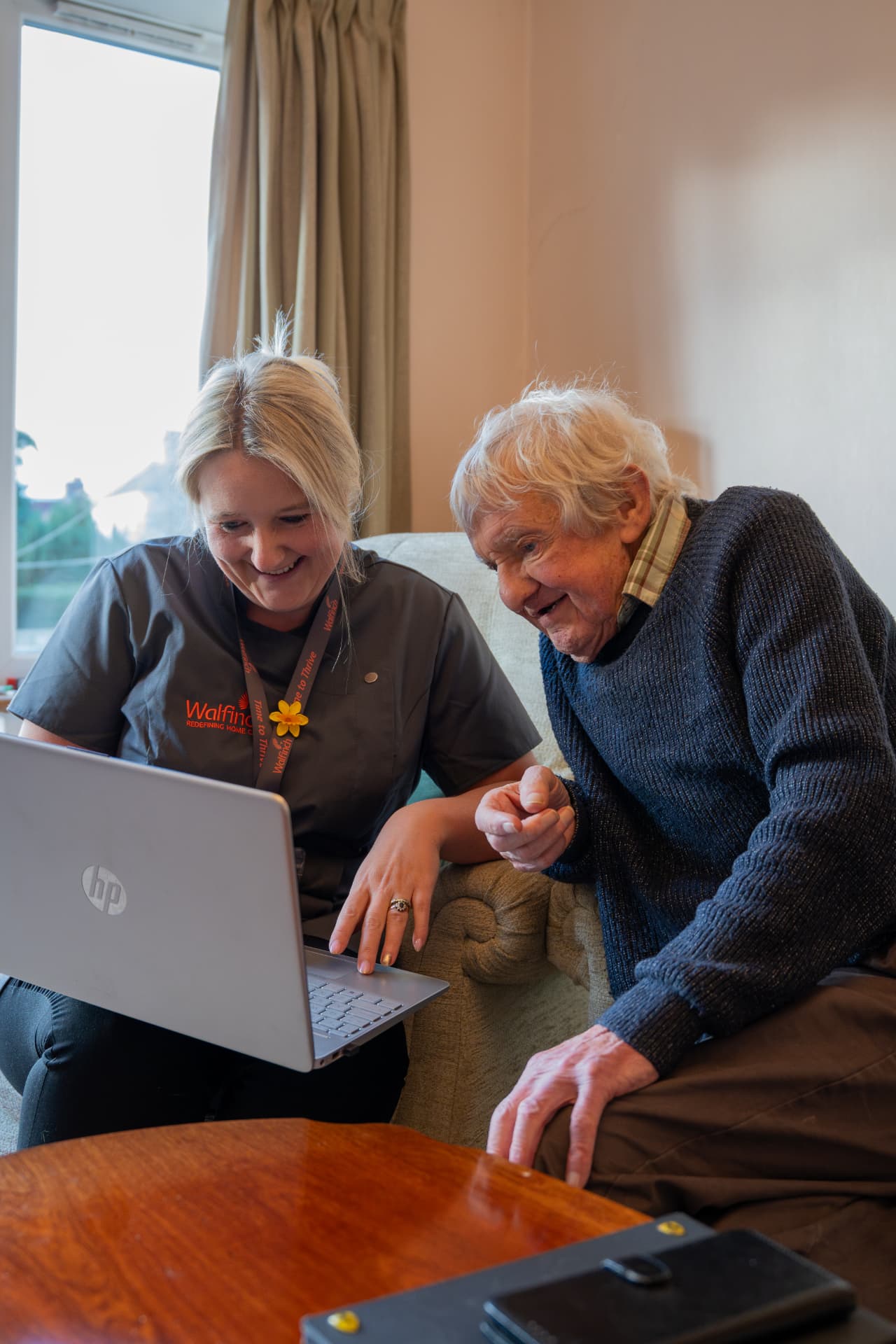 A Walfinch Newcastle carer and an older client looking at a laptop together at home