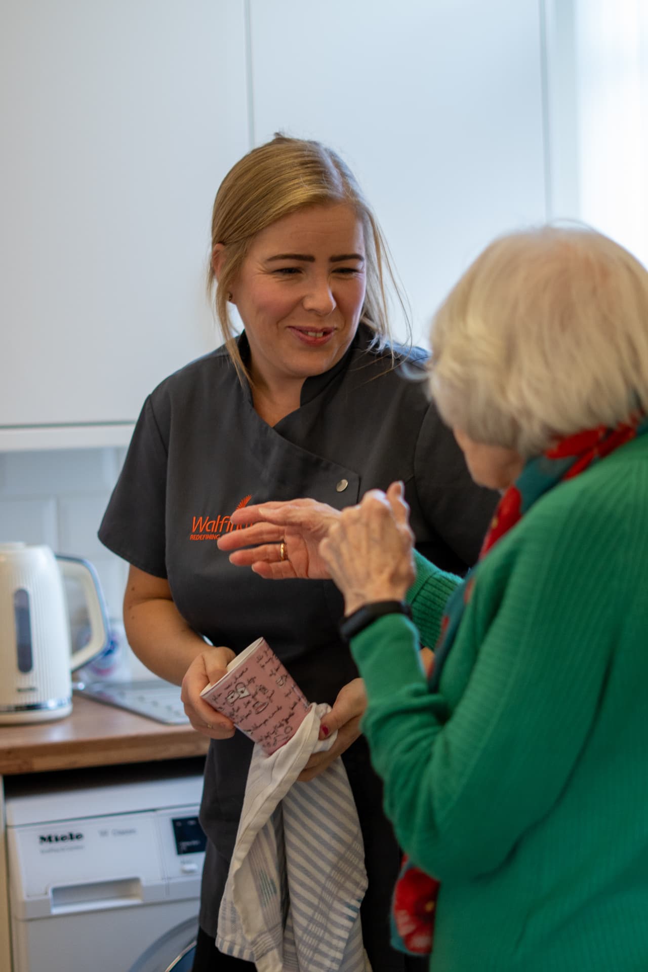 A Walfinch Newcastle carer chatting with an older client in her kitchen