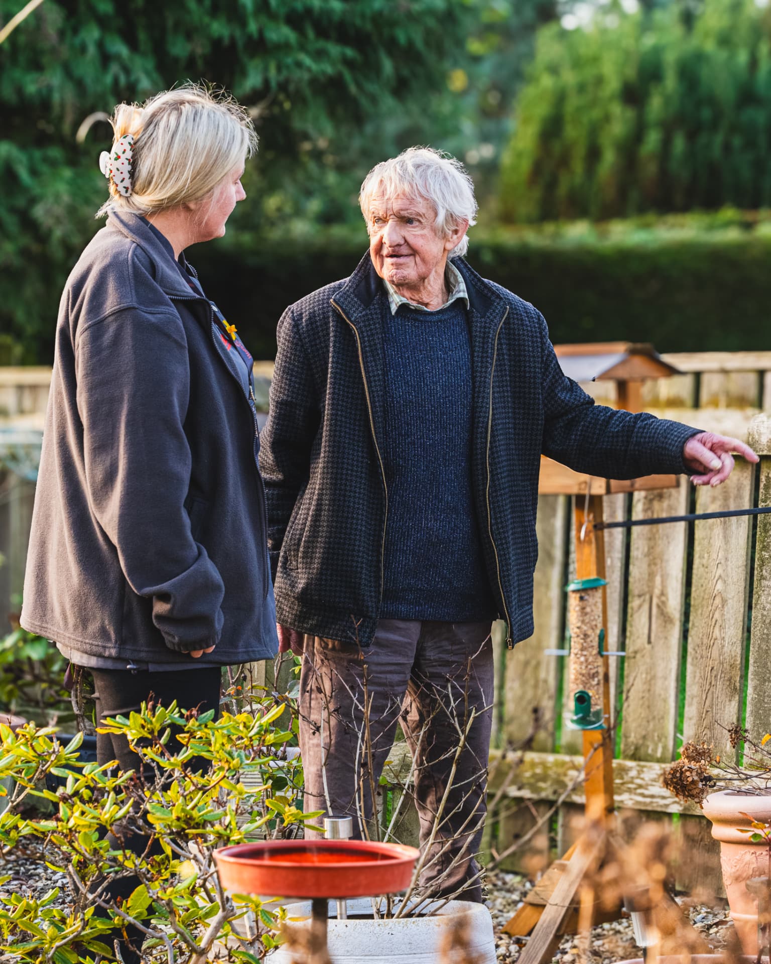 A Walfinch Newcastle carer and an older client sitting on a bench with their dog.